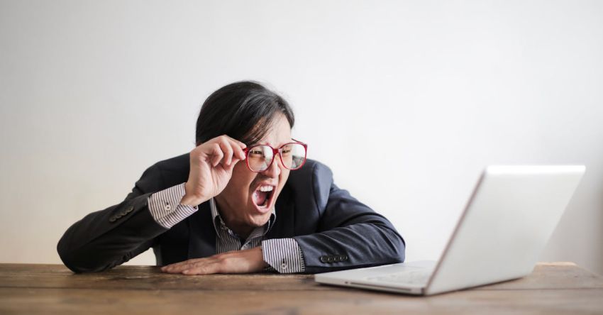Mistakes - Modern Asian man in jacket and glasses looking at laptop and screaming with mouth wide opened on white background